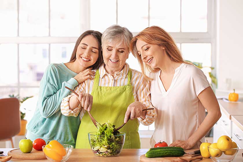 Mature woman with her adult daughter and mother cooking together at home