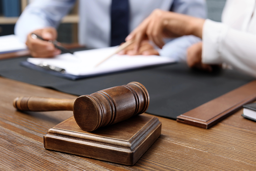 Wooden gavel and blurred lawyer with client on background 